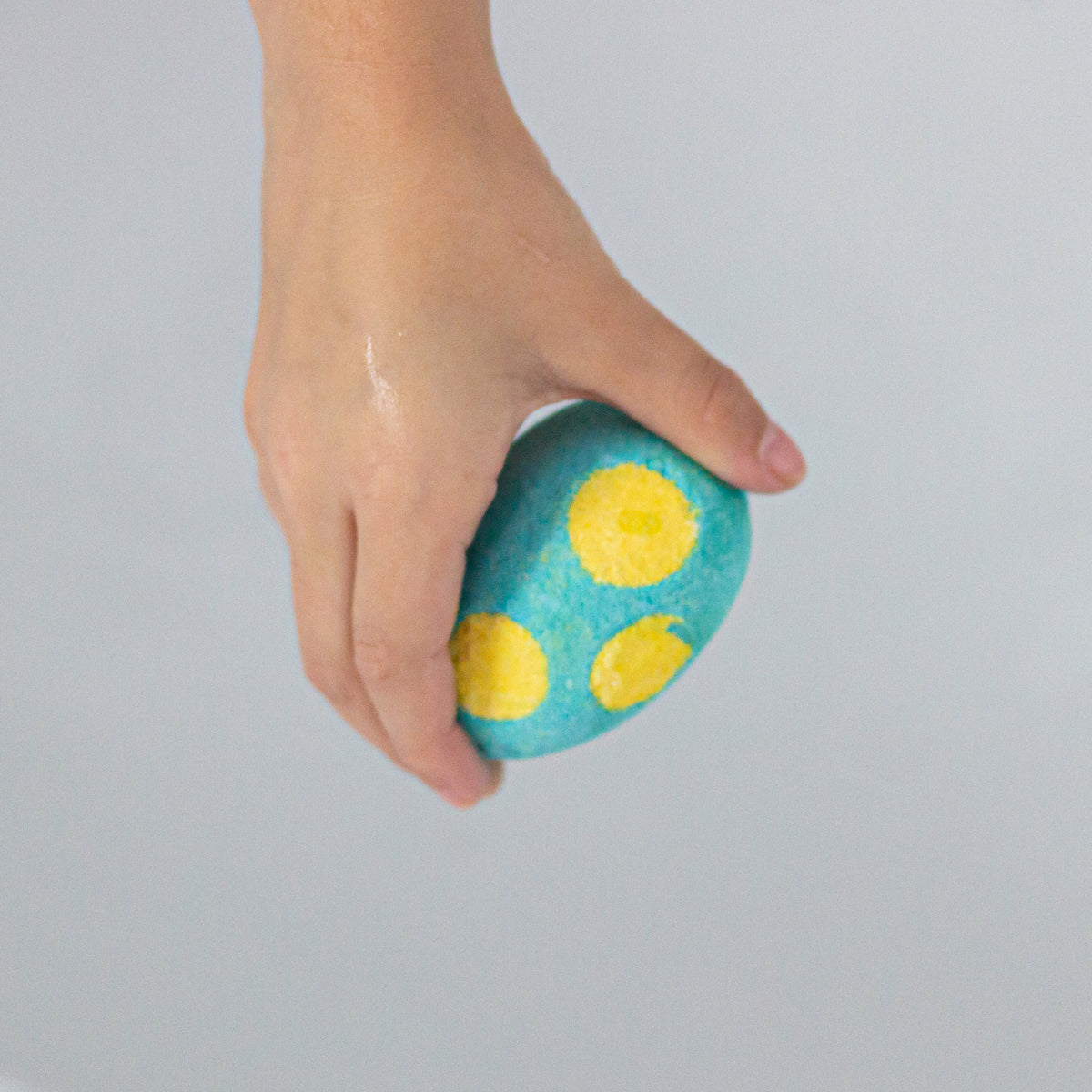 Hand holding a blue spotted Egg Bath Bomb Sprudel