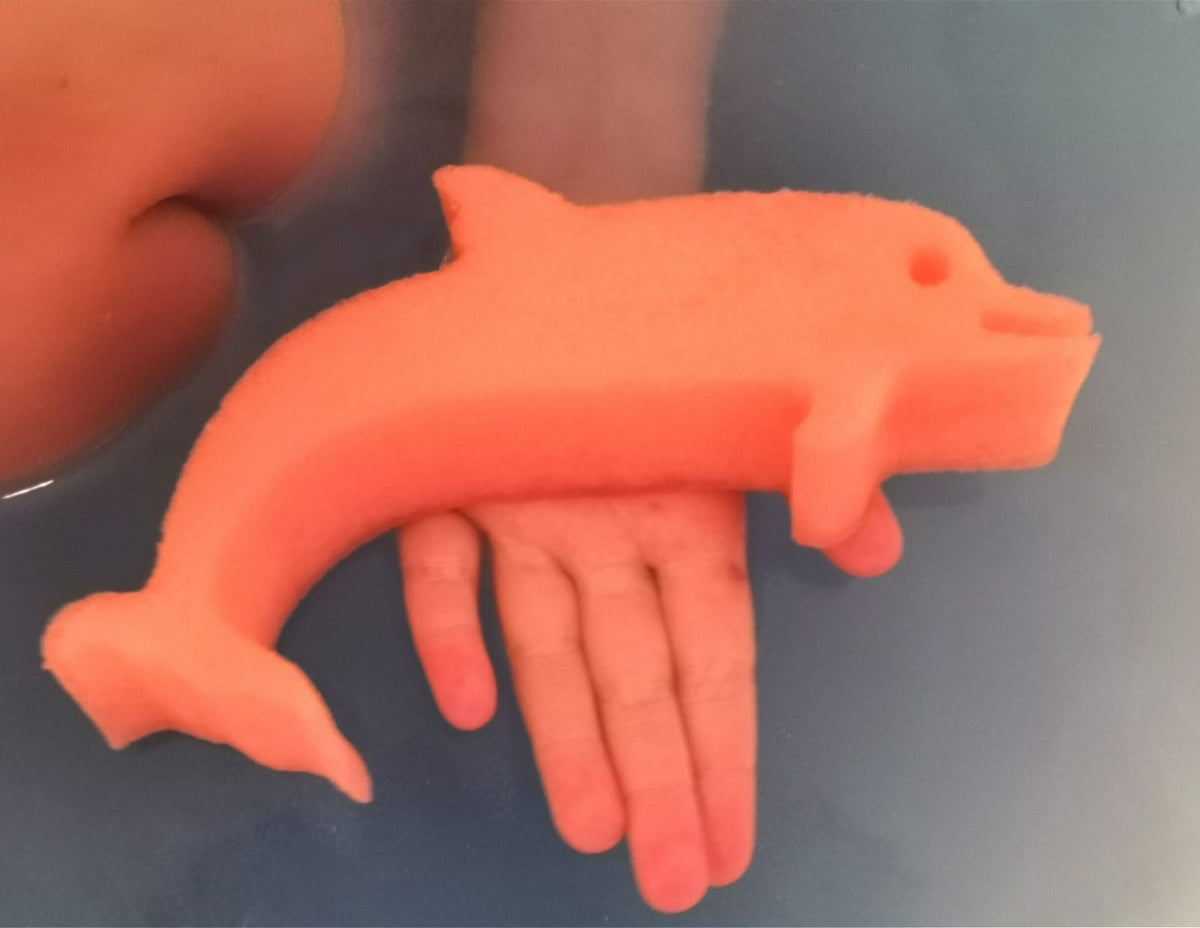 Hand holding a dolphin sponge toy from a Jumbo Bath Bomb Sprudel