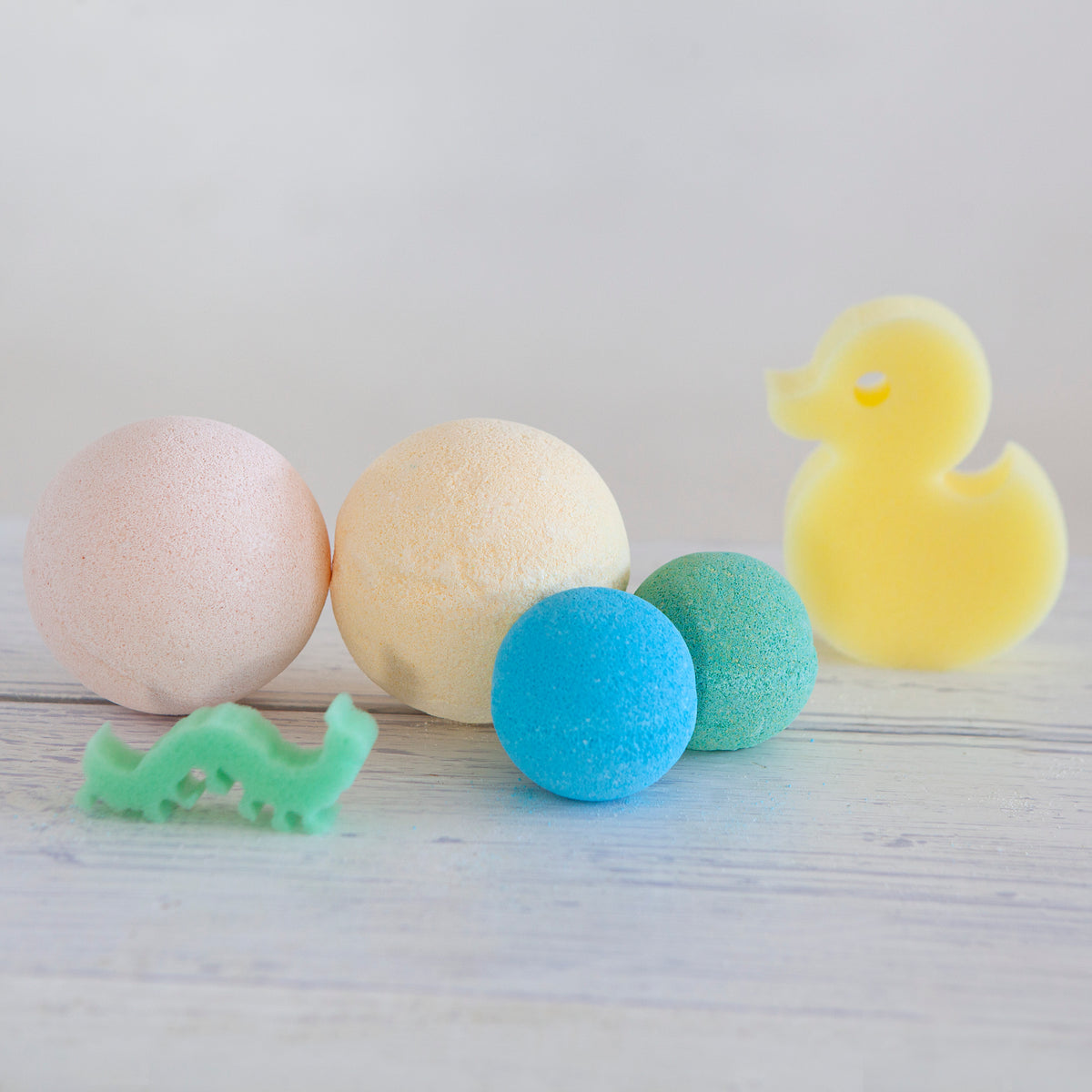 Jumbo and single kids bath bombs with a yellow duck and a green crocodile sponge toy