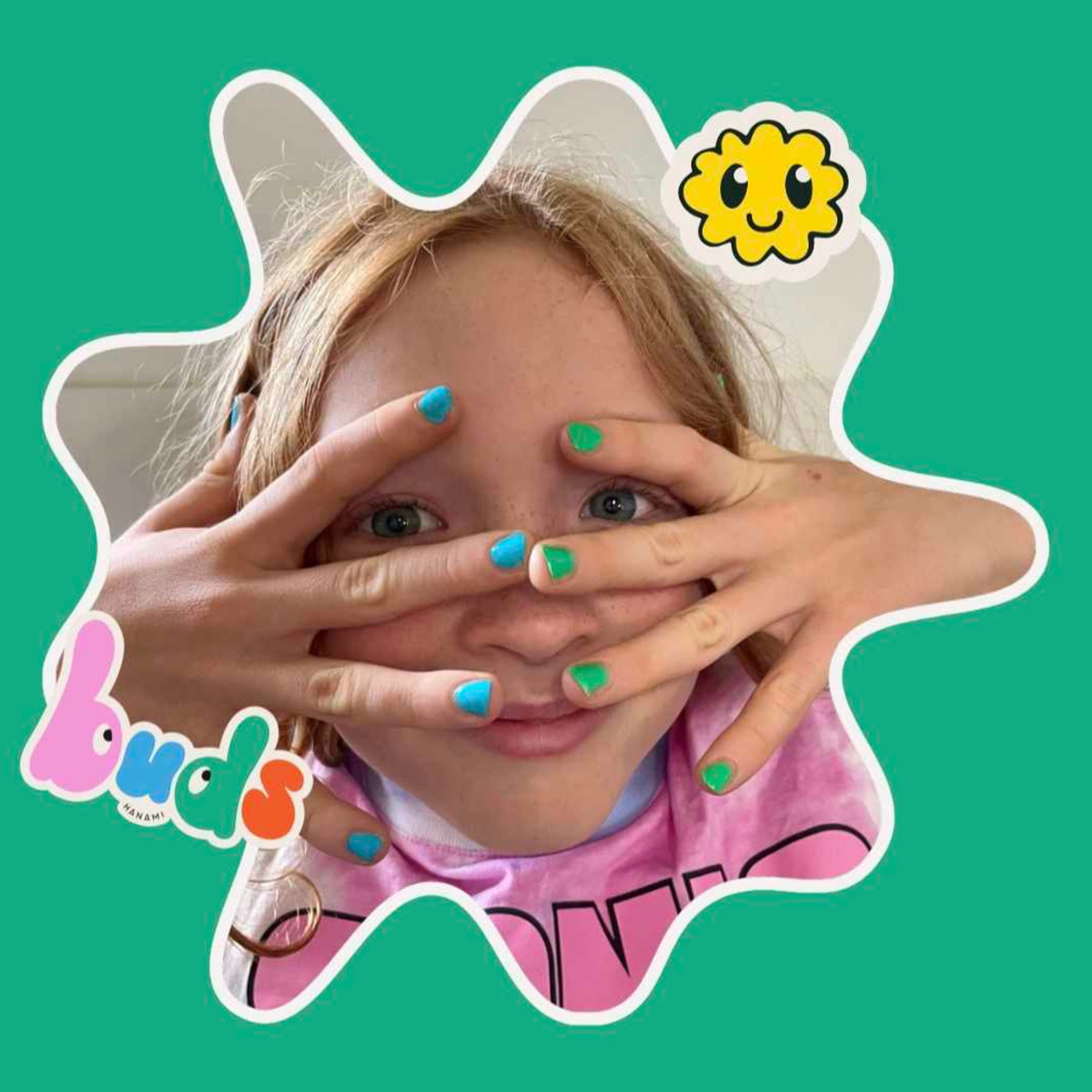 Child with green painted nails peeking through their hands with a smiley sticker on a green background