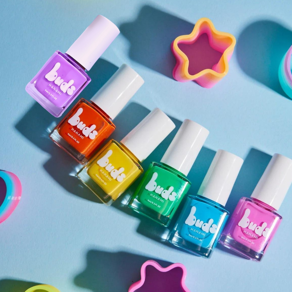 Row of Buds kids nail polish bottles in purple, orange, yellow, green, blue and pink with star-shaped props