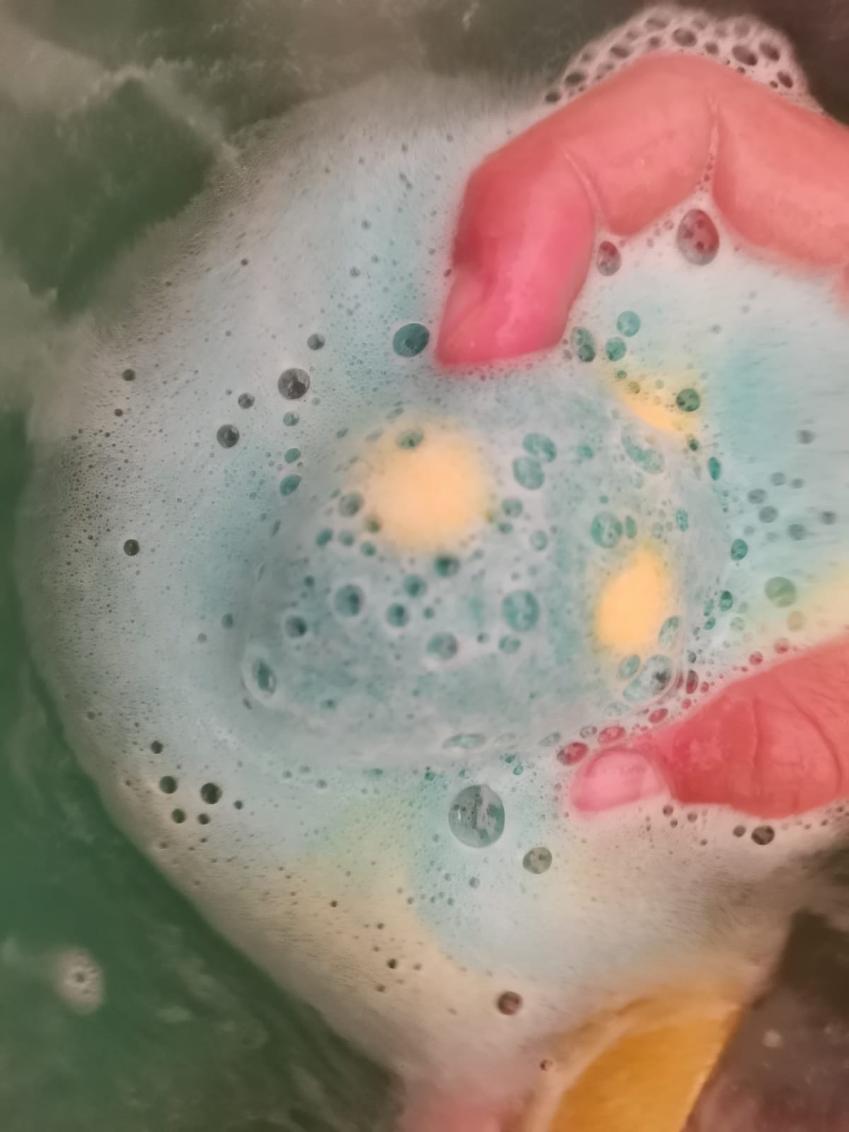 Child's hands holding a spotted Egg Bath Bomb Sprudel fizzing in the bath