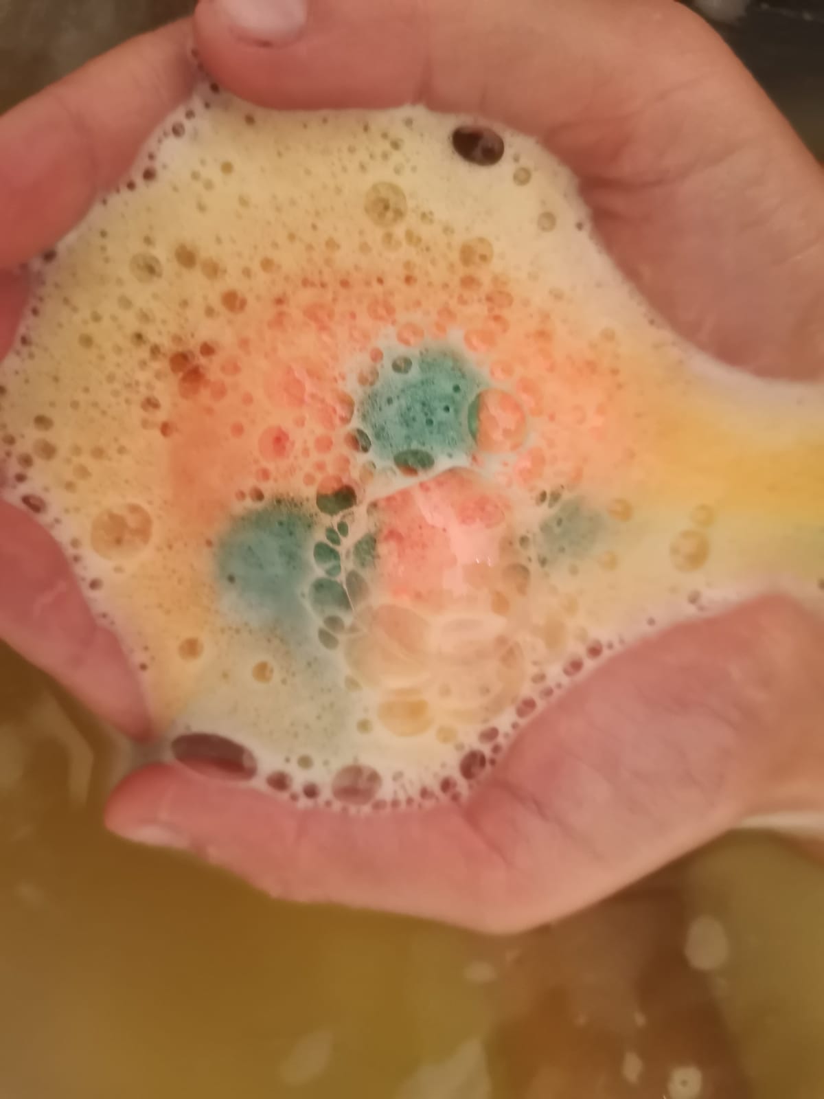 Child's cupped hands holding a fizzing orange Egg Bath Bomb Sprudel