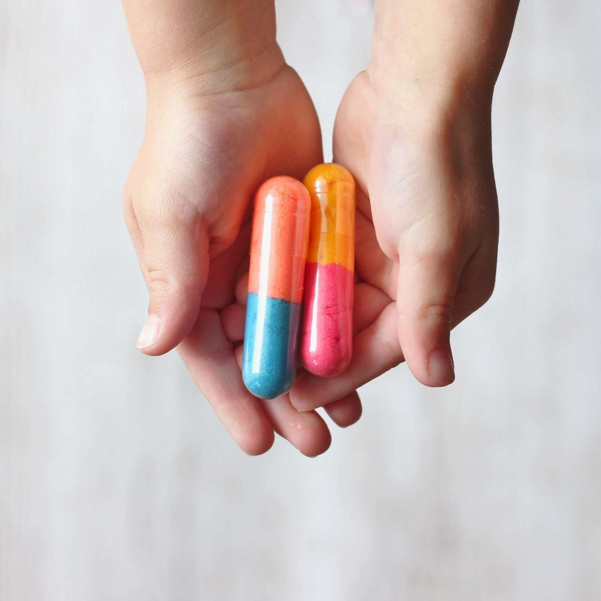 Child's hands holding two Bath Beans capsules