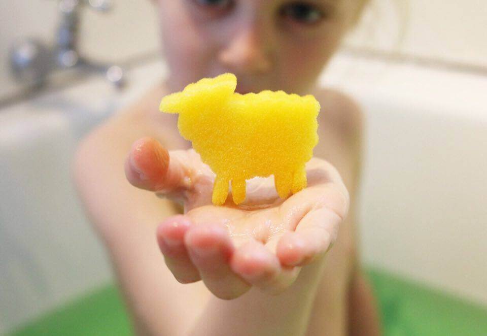 Child holding a sponge toy from a kids bath bomb