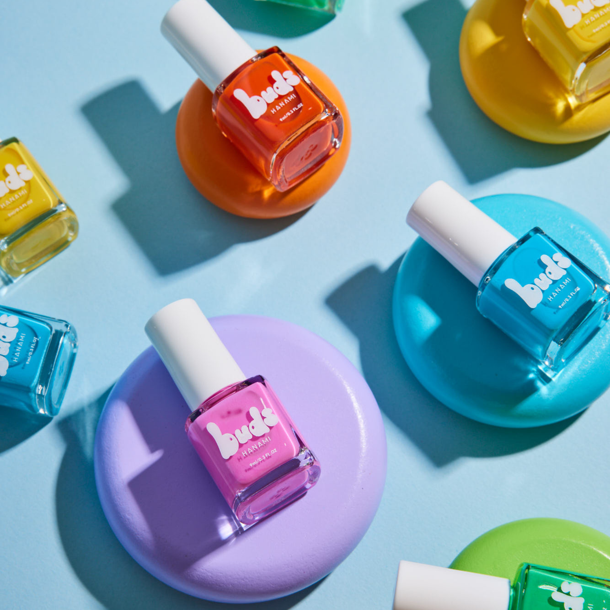Buds kids nail polish bottles in pink, blue, orange and purple on coloured discs