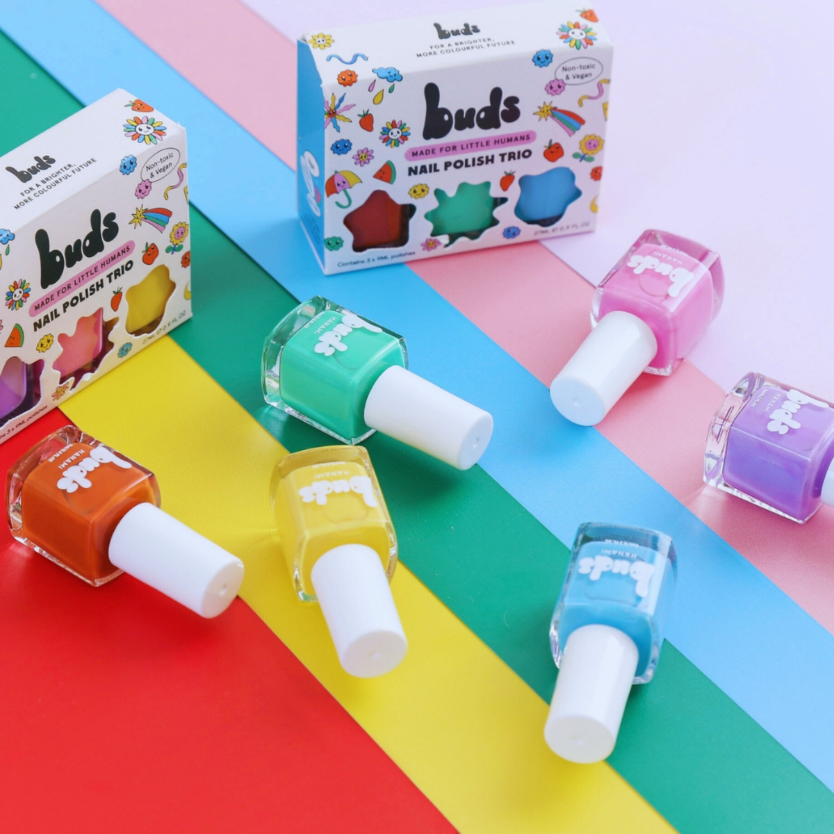 Buds kids nail polish trio boxes and bottles in rainbow colours on a striped background